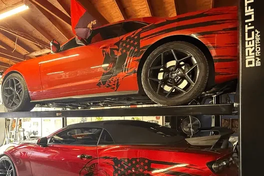 Direct Lift PP8PL four-post car lift storing two red sports cars in a customer’s home garage